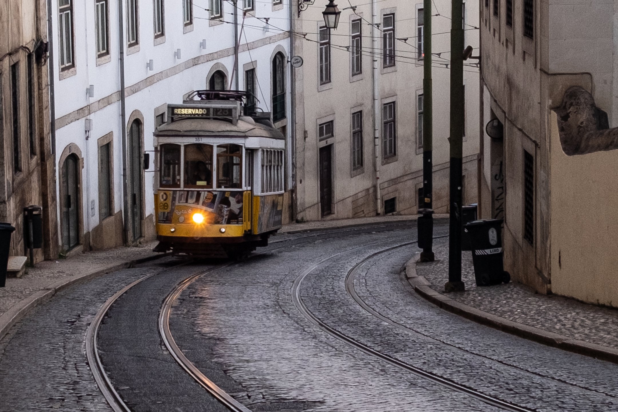 Yellow tram coming up a hill in the early morning